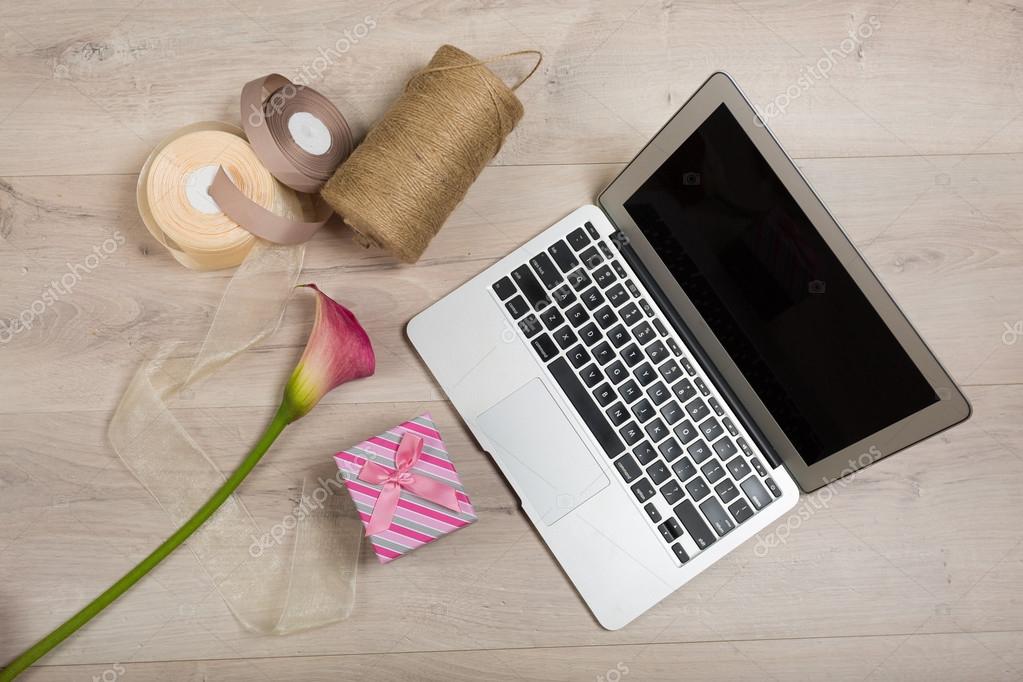 Laptop képernyőjén virágos webshop, mellette virágcsokor