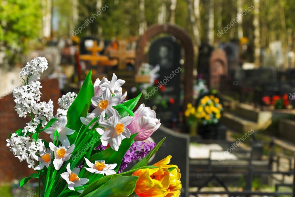 Hosszúkás sírcsokor lágy zöldekkel és fehér virágokkal egy síron elhelyezve